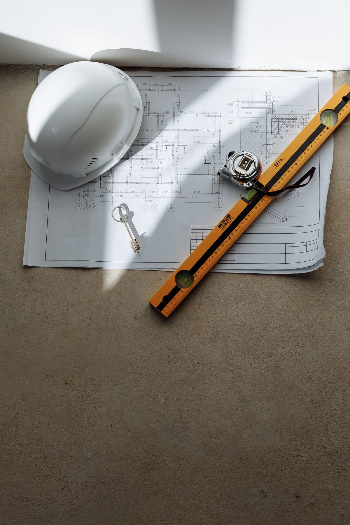 Site helmet, spirit level and measuring tape on a set of building plans